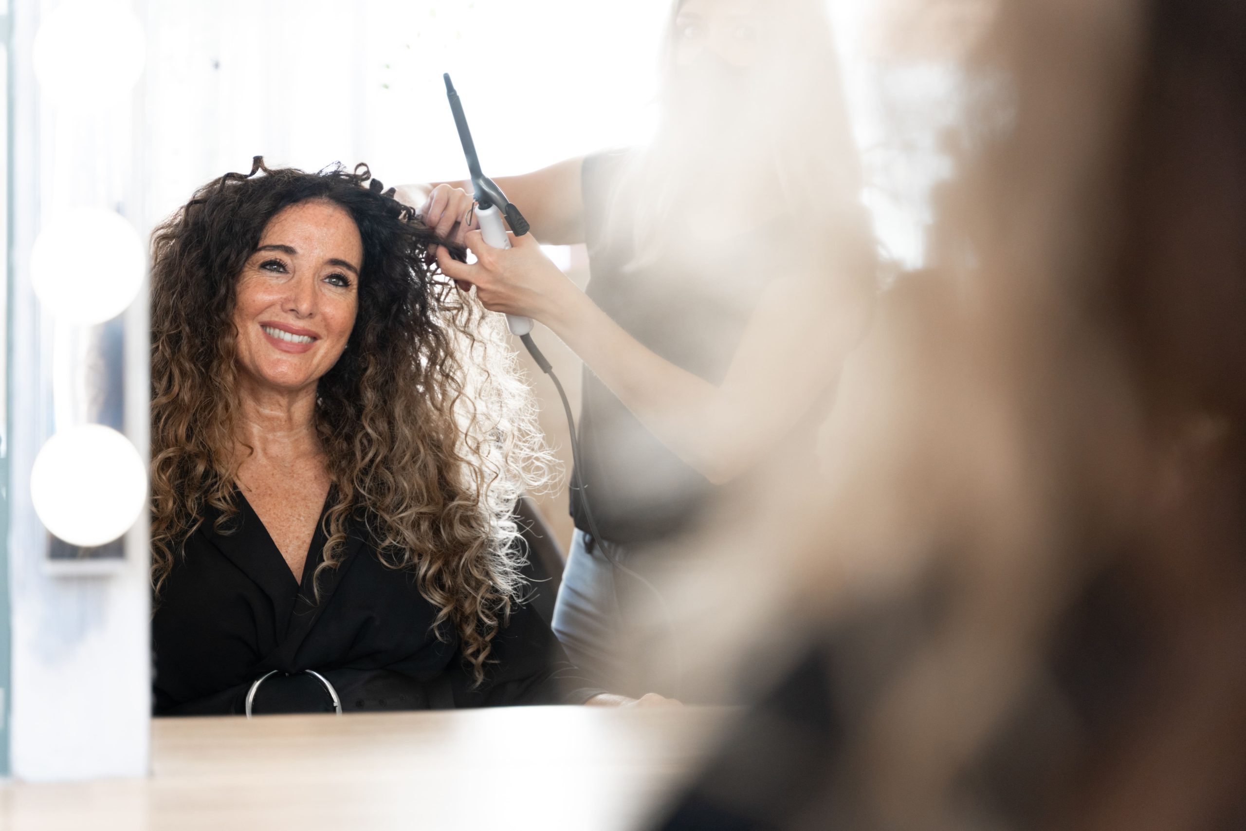 Peluquera realizando peinado profesional con rizador en salón de belleza
